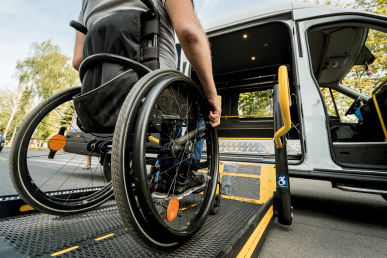 Person loading a wheelchair onto the ramp of an accessible van